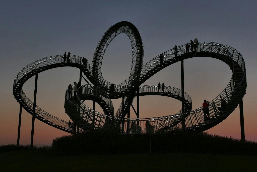 Silhouette of people walking on a spiral staircase against a mesmerizing sunset.